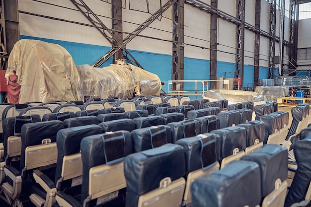 Убирает пассажирские сиденья в ожидании уборки в авиационном ангаре
