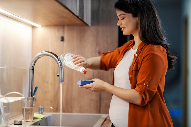 A tidy pregnant woman is doing dishes in kitchen