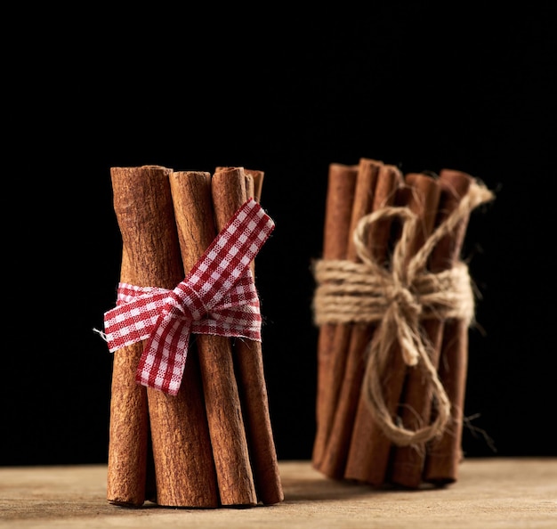 Photo tied bunch of brown cinnamon sticks on a brown wooden background close up