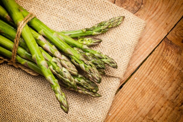 Tied green asparagus on a burlap sack and on a wooden table