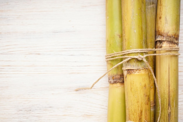 Tied sugarcane on white wooden background space for text closeup Top view