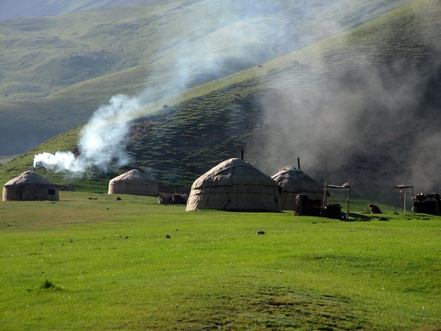 天山山脈、キルギスタン。山、煙の背景に国立キルギスの家パオ