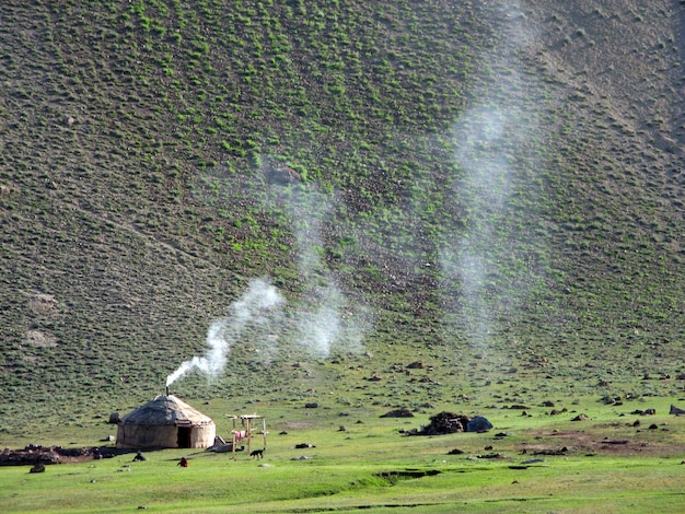 키르기스스탄 톈산산맥. 산, 연기 배경에 국립 키르기즈 하우스 유르트
