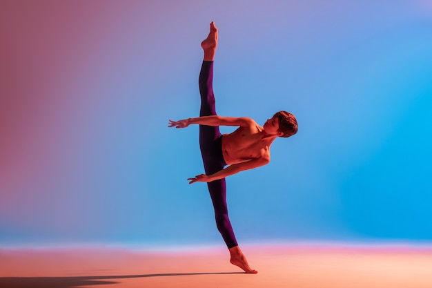 Tiener balletdanser danst op blote voeten onder een gekleurd licht.