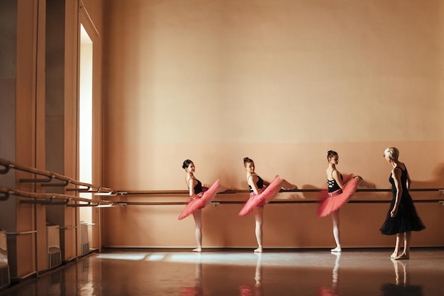 Tiener balletdansers oefenen op een barre terwijl ze een les hebben met hun instructeur op balletschool Copy space