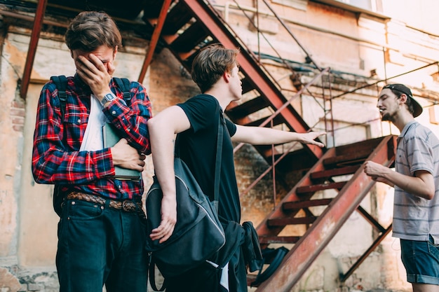 Tiener beschermt zijn vriend tegen agressieve pester. sociale jeugdproblemen. bang huilende slimme jongen. echte vriendschap loyaliteit en ondersteuning concept.