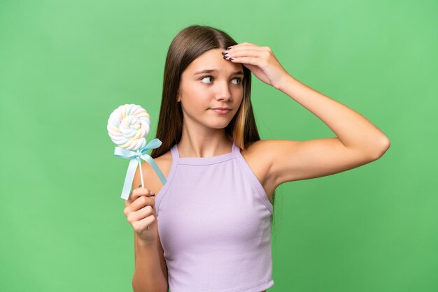 Tiener blank meisje met een lolly over geïsoleerde achtergrond met twijfels en met een verwarde gezichtsuitdrukking