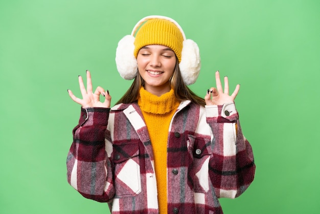 Tiener blank meisje met wintermof over geïsoleerde achtergrond in zen pose