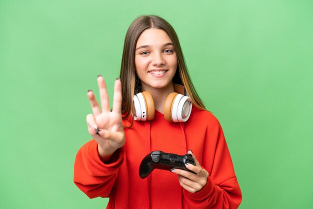 Tiener blank meisje speelt met een videogamecontroller over geïsoleerde achtergrond blij en telt drie met vingers