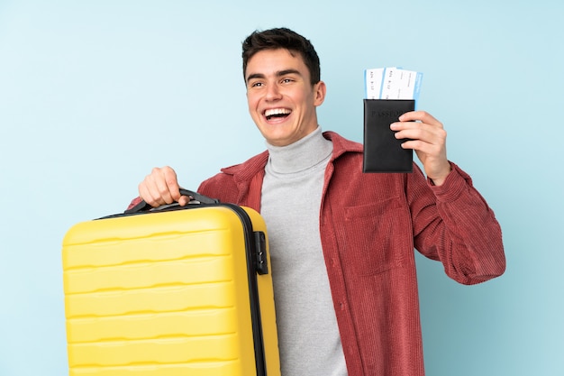 Tiener blanke man op paarse muur in vakantie met koffer en paspoort