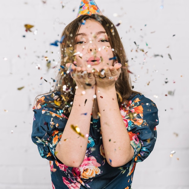 Foto tiener blazende confettien van hand tegen witte achtergrond