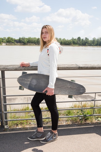 Foto tiener blond meisje buiten met skateboard