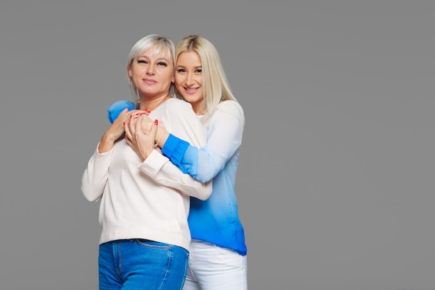 Tiener blonde dochter en rijpe moeder bij het blauwe koesteren als achtergrond