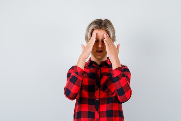 Tiener blonde man in casual shirt die lijdt aan hoofdpijn en er pijnlijk uitziet, vooraanzicht.