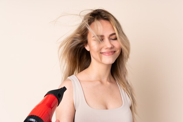 Tiener blondemeisje met haardroger over muur