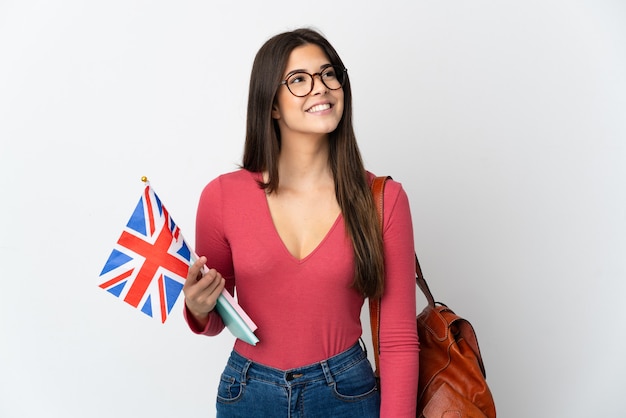 Tiener Braziliaans meisje dat een vlag van het Verenigd Koninkrijk houdt die op witte muur wordt geïsoleerd die een idee denkt terwijl het omhoog kijken