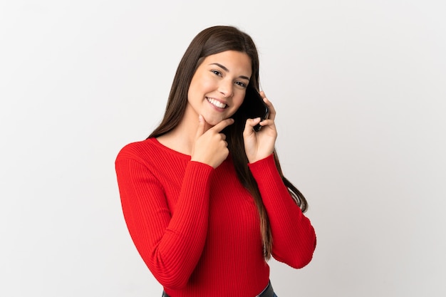 Tiener Braziliaans meisje met behulp van mobiele telefoon over geïsoleerde witte achtergrond gelukkig en lachend
