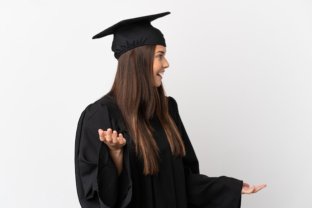 Tiener Braziliaanse universitair afgestudeerd over geïsoleerde witte achtergrond met verrassingsuitdrukking terwijl hij opzij kijkt looking