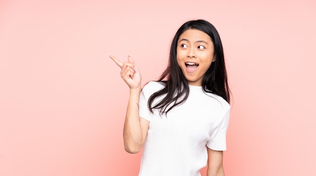 Tiener Chinese vrouw die op roze muur van plan is de oplossing te realiseren terwijl hij een vinger opheft