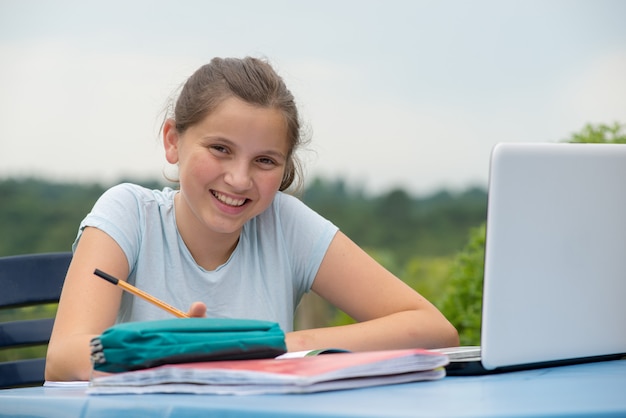 Tiener die haar huiswerk in de tuin doet