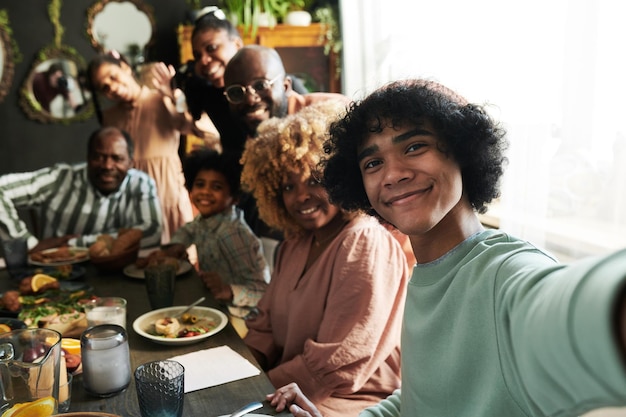 Tiener die selfie portret van zijn grote familie maakt tijdens het vakantiediner aan tafel