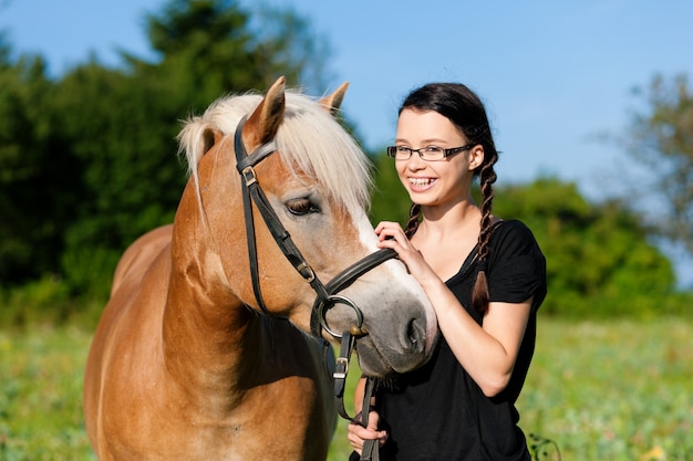 Tiener die zich op een weide in de zomer met haar paard bevindt