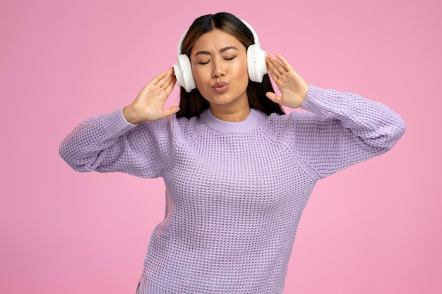 Tiener in koptelefoon genieten van favoriete nummers geïsoleerd over roze achtergrond