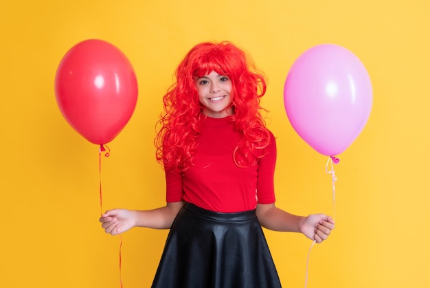 Tiener jongen glimlach met feestballon op gele achtergrond