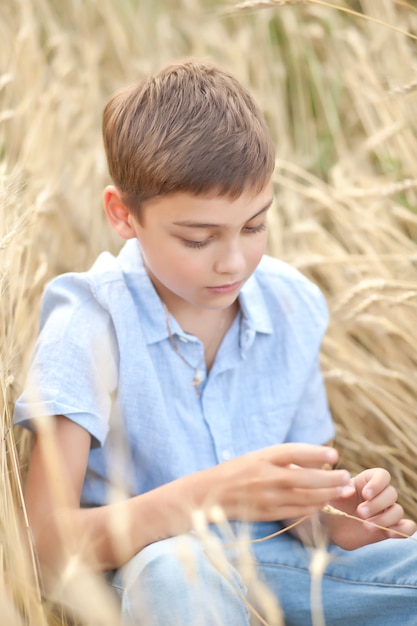 Tiener jongen jongen in tarweveld in een zomerdag.