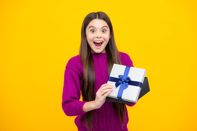 Tiener kind met geschenkdoos op gele geïsoleerde achtergrond Cadeau voor kinderen verjaardag Kerstmis of Nieuwjaar huidige doos Opgewonden gezicht Verbaasde uitdrukking vrolijk en blij