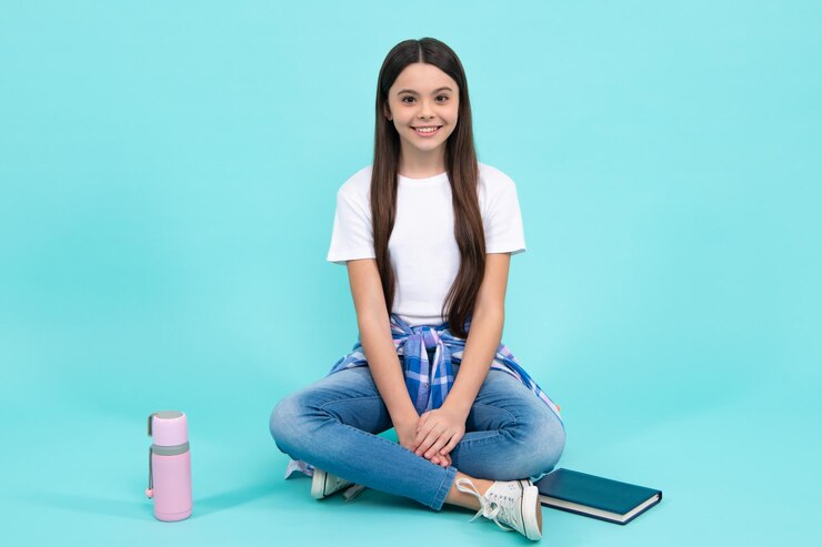 Foto tiener levensstijl sportief tienermeisje met skateboard mode kind in trendy stijl op blauwe achtergrond gelukkig tiener positieve en lachende emoties van tienermeisje