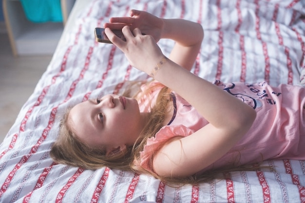 Tiener liggend op haar achterbed en kijkt in de telefoon