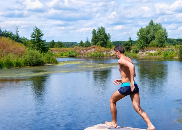 Tiener loopt op een houten brug, sprint om in de rivier te springen. S