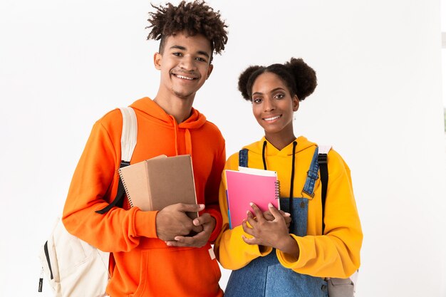 tiener man en vrouw dragen rugzakken met schriften, geïsoleerd over witte muur