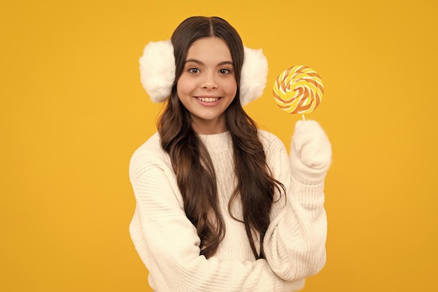 Tiener meisje eet suiker lolly Snoep en snoep voor kinderen Kind eet lolly popsicle over gele geïsoleerde achtergrond Yummy karamel snoepwinkel Gelukkig lachend meisje