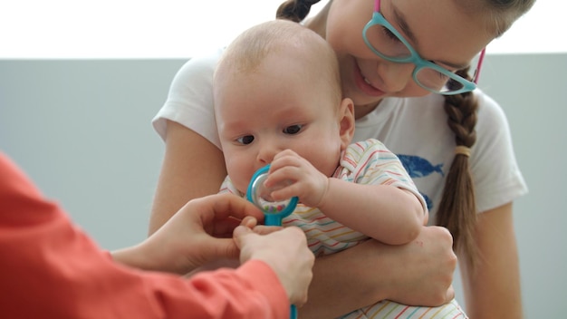 Tiener meisje houdt baby met speelgoed Zusje houdt broertje kind vast