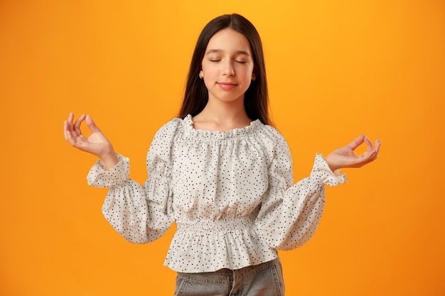 Tiener meisje staande in zen pose tegen gele achtergrond