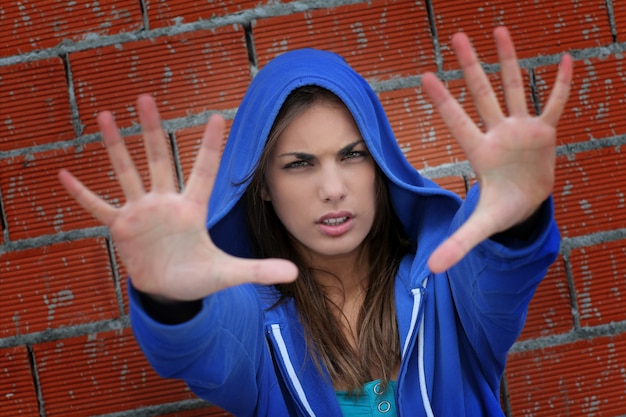 Tiener met blauwe sweater die hand toont aan camera