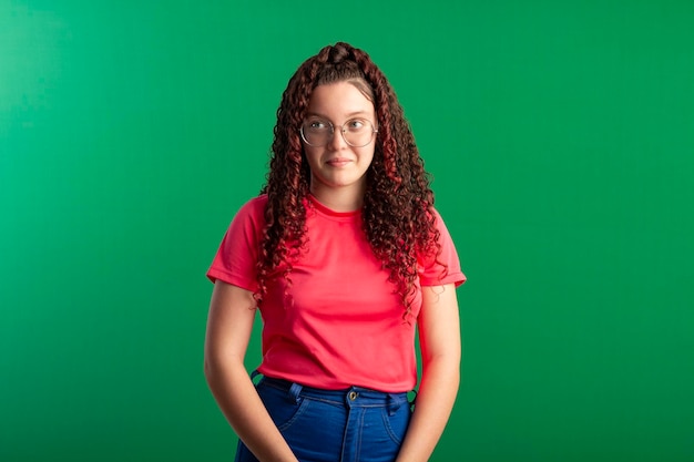 Tiener met bril in leuke poses op een studiofoto met een groene achtergrond, ideaal om bij te snijden