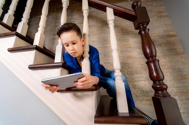 Tiener met tablet op trappen. Van onderaf bekijken.