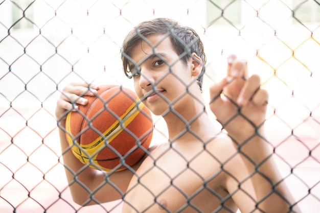 Tiener op stadsspeelplaats met basketbalbal