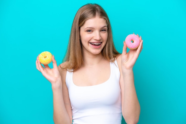 Tiener Russisch meisje geïsoleerd op blauwe achtergrond met donuts met gelukkige expressie