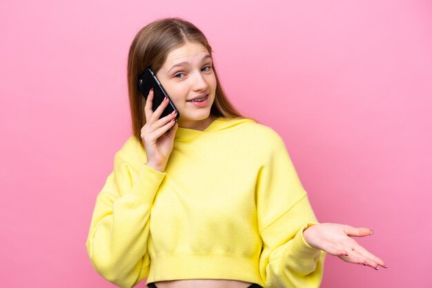 Tiener Russisch meisje geïsoleerd op roze achtergrond houdt een gesprek met de mobiele telefoon met iemand