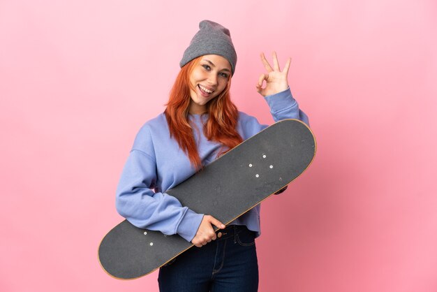 Tiener russisch meisje op roze met een skate en doet ok teken