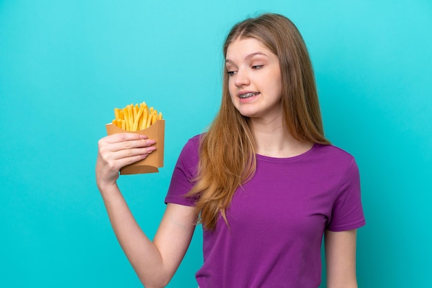 Tiener Russisch meisje vangen van frietjes geïsoleerd op blauwe achtergrond met happy expression