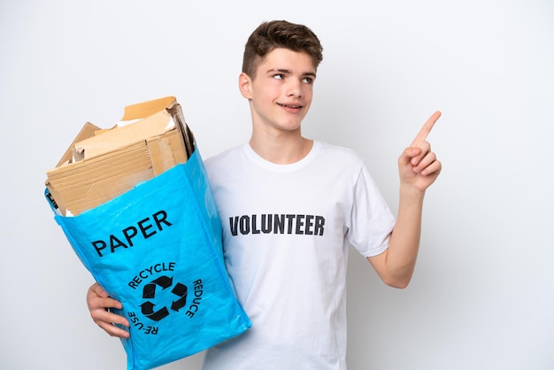 Tiener Russische man met een recyclingzak vol papier om te recyclen geïsoleerd op een witte achtergrond en wijst op een geweldig idee