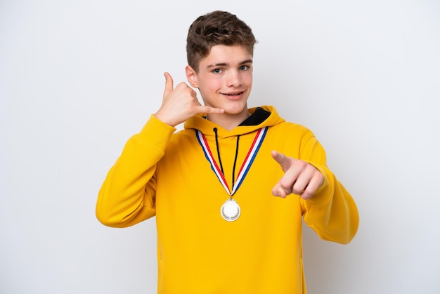 Tiener Russische man met medailles geïsoleerd op een witte achtergrond die telefoongebaar maakt en naar voren wijst