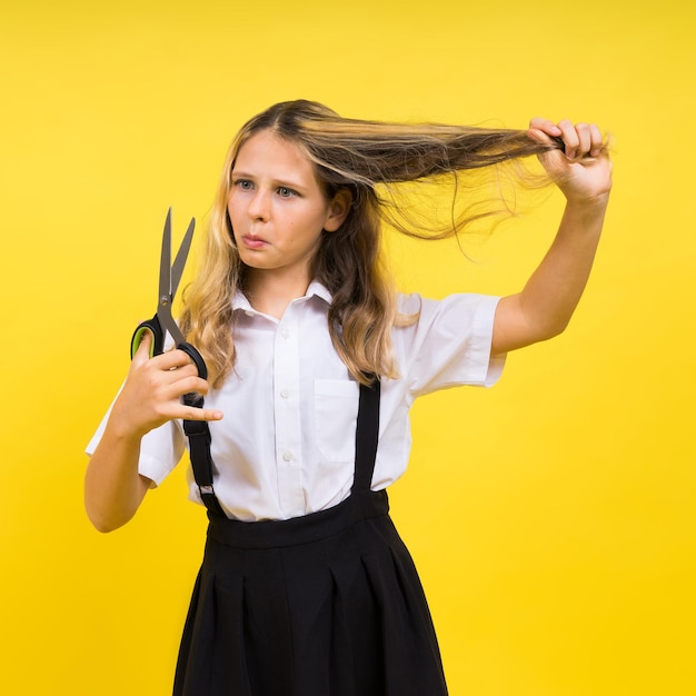 Tiener schoolmeisje met schaar geïsoleerd op gele achtergrond Kind creativiteit kunsten en ambachten