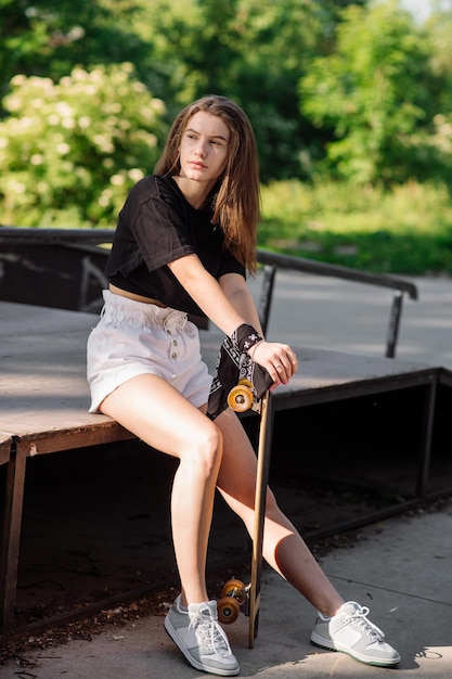 Tiener skater meisje met een skateboard zit in het skaters park