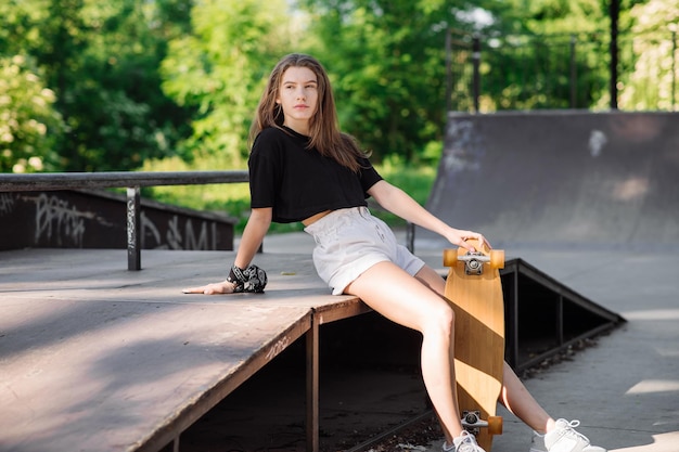 Tiener skater meisje met een skateboard zit in het skaters park